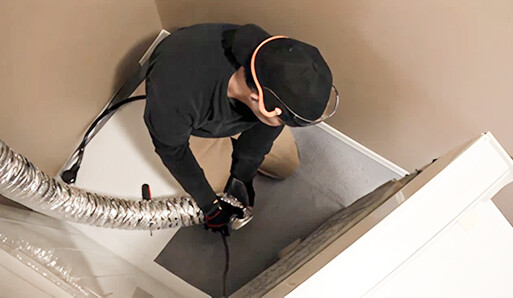 Technician accessing and cleaning dryer vent system in ceiling or crawl space